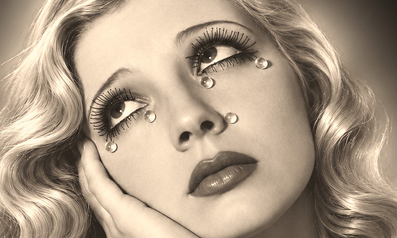 A woman looking upward, glass droplets resting on her lashes.